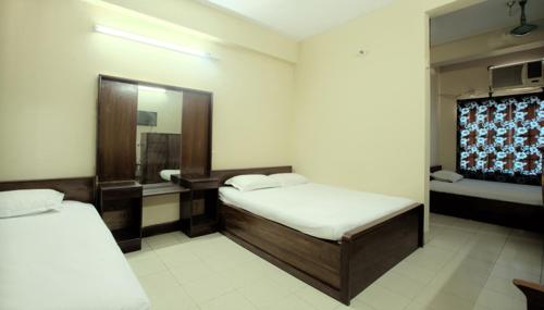a hotel room with two beds and a mirror at Hotel Sea Queen in Cox's Bazar