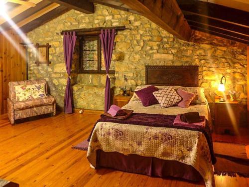 a bedroom with a bed and a stone wall at Casa Rural Yolanda para 5 personas in Arangas
