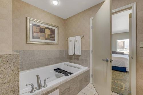 a bathroom with a bath tub and a bed at Ultimate Las Vegas Getaway One Bedroom Suite with Balcony, Kitchen, Gym, Pool & Free Parking in Las Vegas
