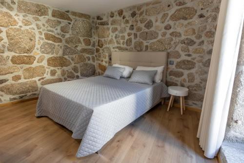 1 dormitorio con 1 cama en una pared de piedra en Carvalho Village, en Fafe