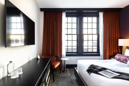 um quarto de hotel com uma cama e duas janelas em Hotel Thaxter em Portsmouth
