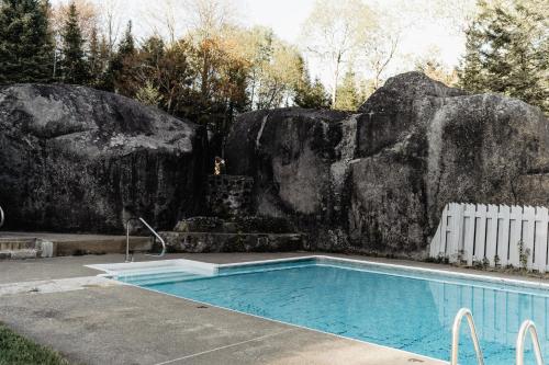 a swimming pool in front of a rock wall at Le Couvent Val-Morin in Val-Morin