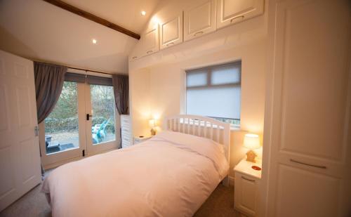 een slaapkamer met een wit bed en een raam bij Beckside Cottage, Netherby, near Carlisle in Longtown