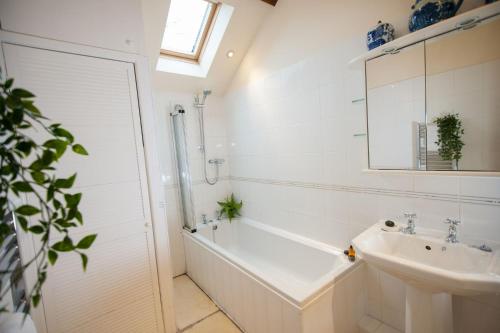 a white bathroom with a tub and a sink at Beckside Cottage, Netherby, near Carlisle in Longtown