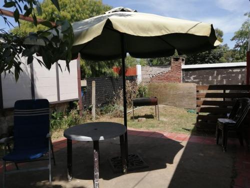 un patio con sombrilla, mesa y silla en Apartamento 2 ambientes + baño Las Toscas SUR, en Las Toscas