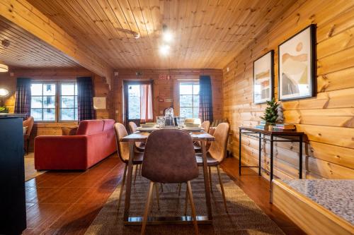 a dining room with a table and a red couch at Chalé de Montanha com sons de rio in Cortes do Meio