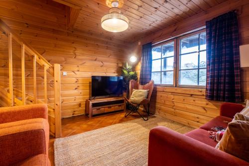 a living room with wooden walls and a tv and a couch at Chalé de Montanha com sons de rio in Cortes do Meio