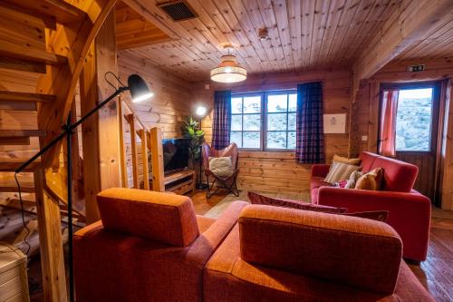 a living room with a couch and chairs in a cabin at Chalé de Montanha com sons de rio in Cortes do Meio