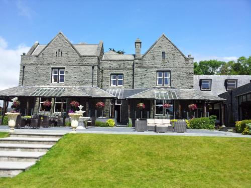 a large stone building with a lawn in front of it at Bron Eifion Hotel in Criccieth