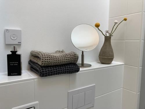 a mirror on a shelf with a vase and towels at RaumAusbeute Design Apartment Hoher Priester in Detmold