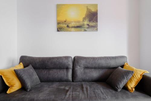a couch with yellow pillows and a painting on the wall at Ana Kraljevo in Kraljevo