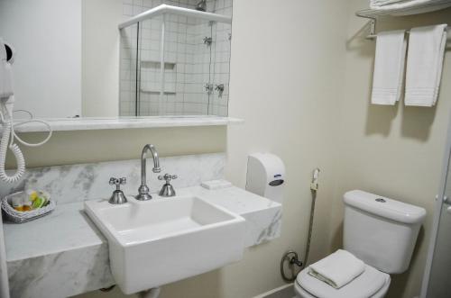 a white bathroom with a sink and a toilet at Guararema Parque Hotel in Guararema