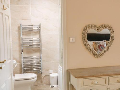 een badkamer met een hartspiegel aan de muur bij The Hayloft at Tennant Barn in Skipton