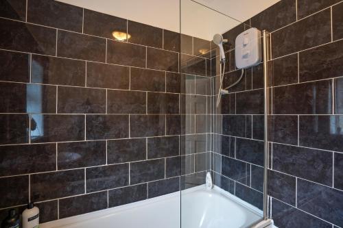 a bathroom with a tub and a glass shower at 3 Bed Flat-Close to City Centre in Lemington