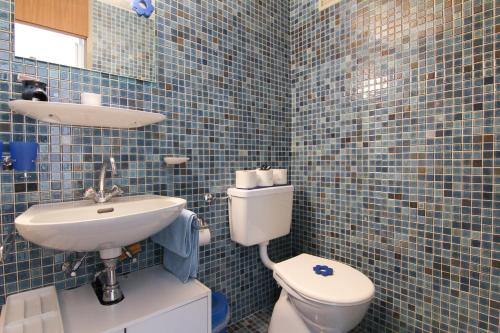 a blue tiled bathroom with a toilet and a sink at Casa Yolanda Familienwohnung Mireille in Fieschertal