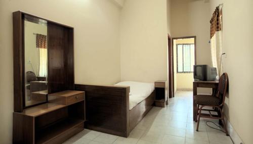 a bedroom with a bed and a desk and a mirror at Hotel Sea Queen in Cox's Bazar