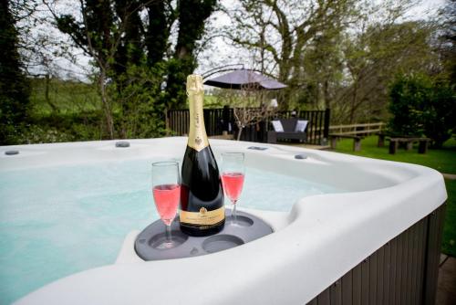 Una botella de champán y dos copas en una bañera. en The Snug, Netherby, near Carlisle, en Longtown