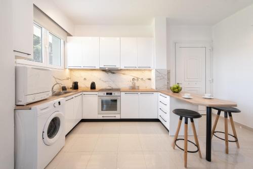 a white kitchen with white cabinets and a wooden table at Island Hills in Rhodes Town