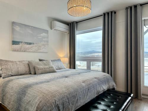 a bedroom with a bed and a large window at Motel le Point de Vue in La Malbaie