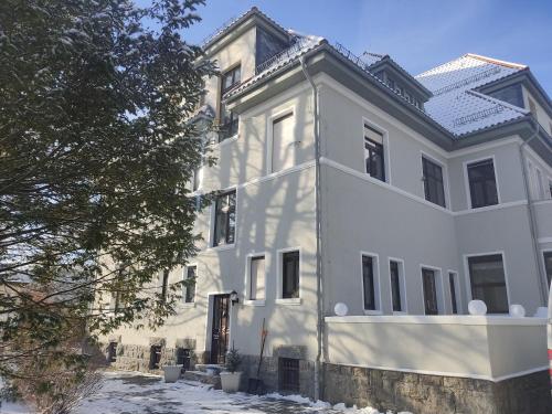 a white house with snow on the ground at Parkvilla Köhler in Zella-Mehlis