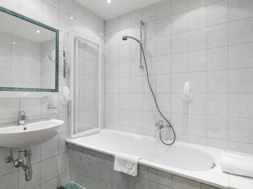 a white bathroom with a tub and a sink at Posthotel Strengen am Arlberg in Strengen