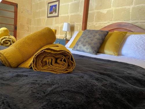 - une chambre avec 2 lits et des oreillers jaunes dans l'établissement Haven Farmhouse With Private Pool, à L-Għarb