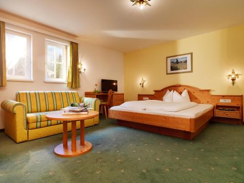 StrengenにあるPosthotel Strengen am Arlbergのベッドルーム1室(ベッド1台、ソファ、テーブル付)