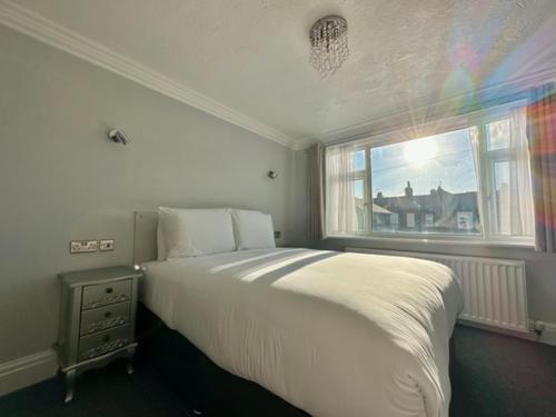 a bedroom with a white bed and a window at Bromwell Court in Llandudno