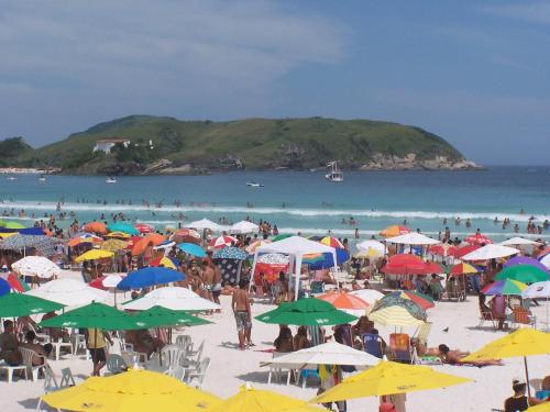 eine Menschenmenge an einem Strand mit Sonnenschirmen in der Unterkunft Zênit Hostel da Cris in Cabo Frio