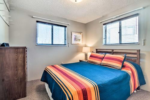 a bedroom with a bed and two windows at Updated Condo with Views and Deck Less Than 1 Mi to Grand Lake in Grand Lake