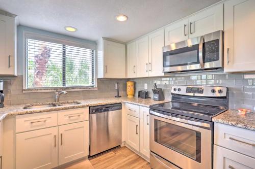 a kitchen with white cabinets and stainless steel appliances at Beachside St Augustine Resort Condo, 6 Mi to Dtwn! in Coquina Gables