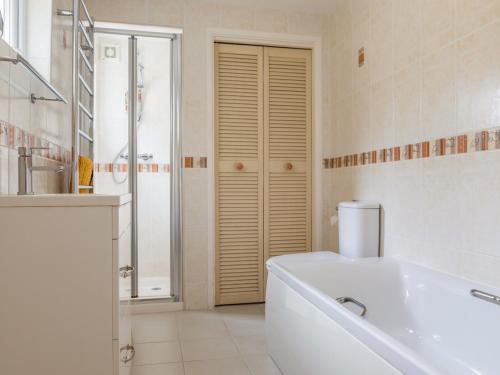 a white bathroom with a tub and a shower at 14a Courtenay Street in Salcombe
