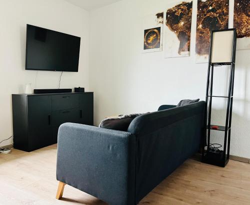 a living room with a blue couch and a television at Das Chorzimmer- Ambiente am Fuße der Burg in Holzhausen