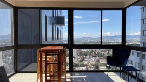 Cette chambre dispose de grandes fenêtres, d'une table et de chaises. dans l'établissement Amplio Departamento 2 Recamaras, à Mexico