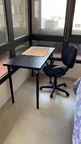 un bureau noir, une chaise, une table et une fenêtre dans l'établissement Amplio Departamento 2 Recamaras, à Mexico