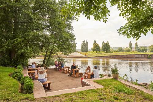 a group of people sitting around tables by a lake at Mill on the Exe in Exeter