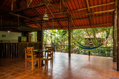 a porch with a hammock and a table and chairs at La Fortuna Natural Green in Fortuna