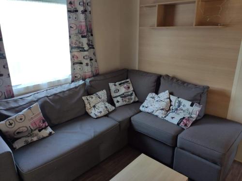 a living room with a couch with pillows on it at Mobil home 2 chambres tout équipé in Hourtin