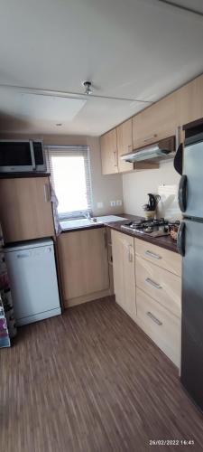 a small kitchen with wooden cabinets and a refrigerator at Mobil home 2 chambres tout équipé in Hourtin