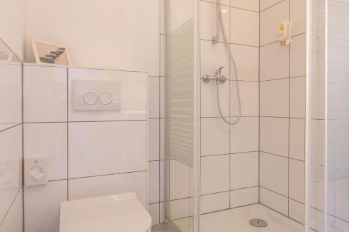 a white bathroom with a shower and a toilet at Apartmenthaus Erlenbach in Erlenbach