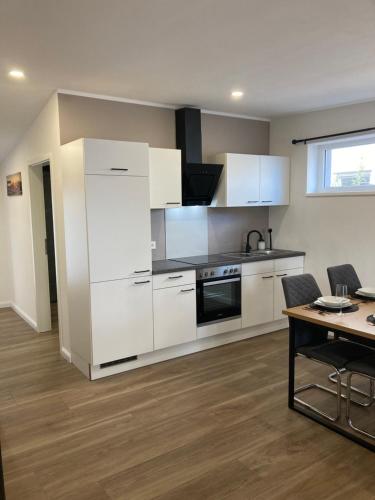 a kitchen with white cabinets and a table at Moderne Ferienwohnung mit Balkon in Herxheim