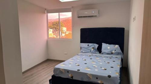 a bedroom with a bed with blue sheets and a window at Apartamentos nuevos, comodos, amplios y moderno OK in Gaira