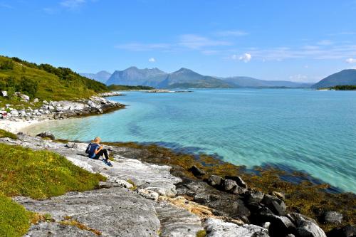 a person sitting on the rocks near the water at Hamn i Senja in Hamn
