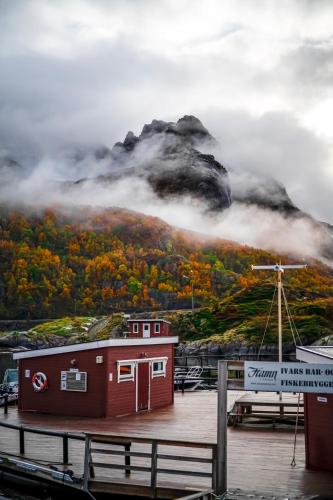 a mountain obscured by clouds with a house and a dock at Hamn i Senja in Hamn