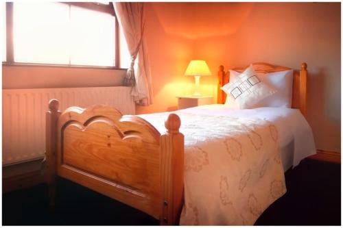 a bedroom with a large wooden bed with a window at McCarthy's Westport in Knockhill and Drinagh