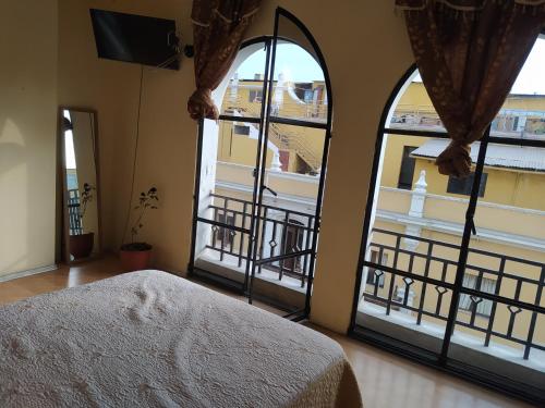 1 dormitorio con ventanas grandes y vistas a un balcón en Apartamento frente al Palacio Gobierno, en Lima