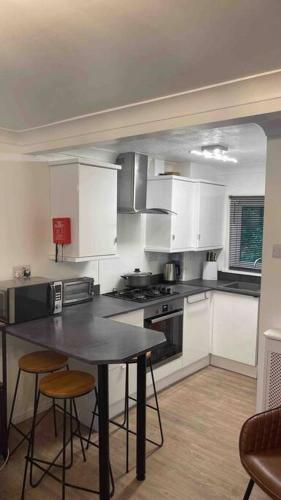 a kitchen with white cabinets and a table and chairs at Chalet 130 on Glan Gwna holiday park in Caernarfon