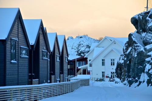 a row of houses in the snow with mountains in the background at Hamn i Senja in Hamn