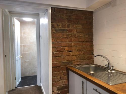 a kitchen with a sink and a brick wall at Comfortable Modern Home, Self Catering Flat, Newly refurbished, town centre, free parking in Cheltenham