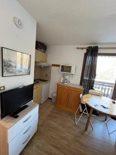 uma sala de estar com televisão e uma mesa com mesa; em Appartement 24m² à la montagne em Arâches-la-Frasse